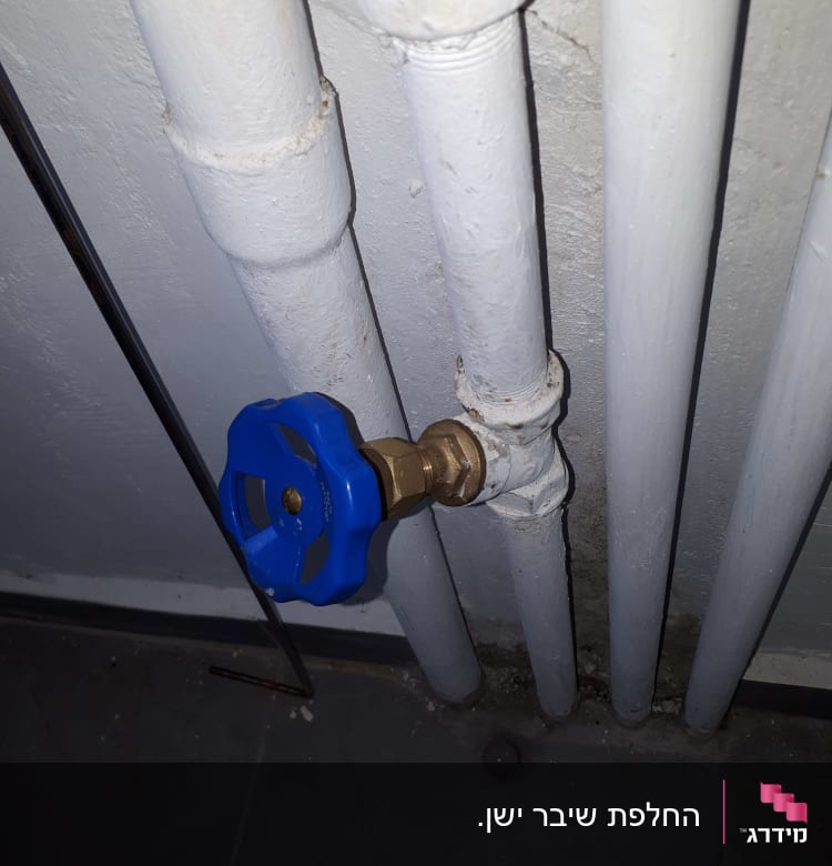 ברז כחול מחובר לצינורות לבנים על קיר